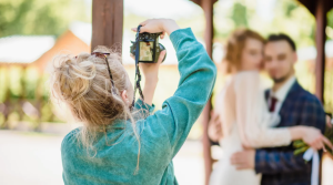 Trouwfotograaf maakt een foto van een bruidspaar tijdens een buitenbruiloft op een zonnige dag.