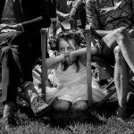 Kleine bruidsmeisje verveelt zich onder de stoelen tijdens een buitenbruiloft, vastgelegd door trouwfotograaf Isabelle Hattink