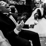 Bruidegom en gasten barsten in lachen uit tijdens een emotioneel en hilarisch trouwmoment, dynamisch vastgelegd door Isabelle Hattink.